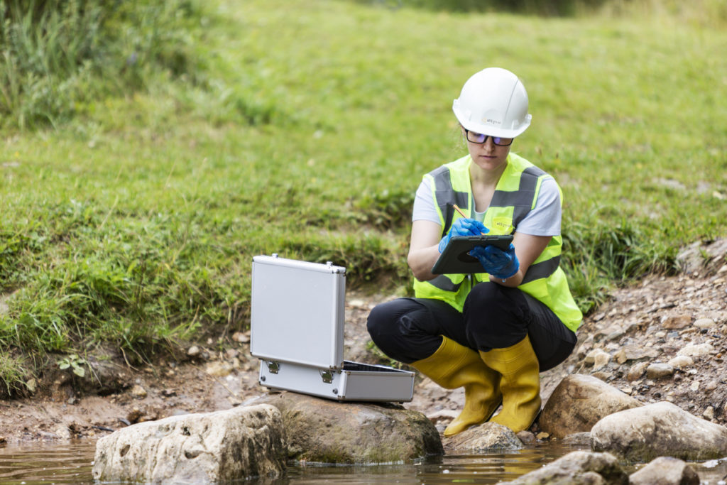 A worker checks for contaminants in the soil and water.