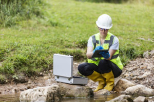 A worker checks for contaminants in the soil and water.
